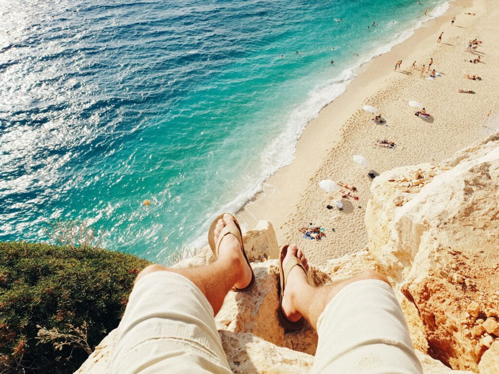 person sitting on cliff above body of water